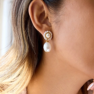 Elegant gold earrings with baroque teardrop pearls worn on ear for a luxury aesthetic