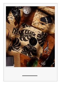 Detail of vintage kraft wrapping paper set with black leaf patterns and hemp rope