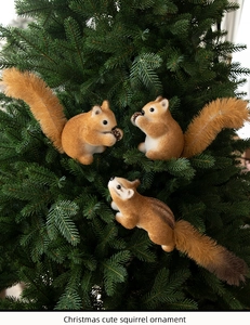 Three cute squirrels with bushy tails as hanging ornaments on a green Christmas tree