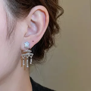 Elegant silver star earrings with spiral tassels and diamonds on a model's ear