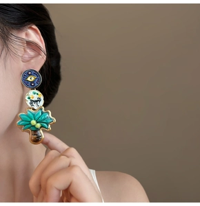 Detail shot of multi-layered drop earrings featuring evil eye and palm tree motifs
