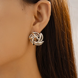 Close-up of silver spiral hollow flower stud earring on model showcasing geometric metal design