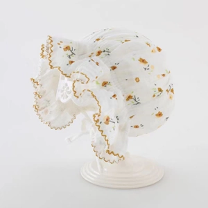 Détail du béguin bébé en coton fleuri avec imprimé jaune et bordure volantée brodée