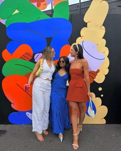 Tre eleganti donne in completo bianco, abito lungo blu e abito a fascia color arancione