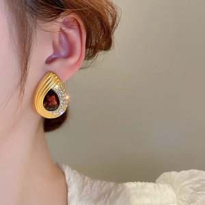 Detailed view of teardrop earring with large red gemstone and sparkling rhinestones