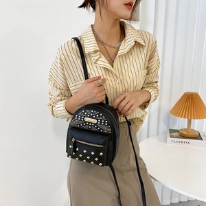 Mini black punk backpack with gold studs and earphone port worn by a model