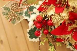 Close-up of red Christmas flowers with gold glitter leaves and rustic burlap ribbon