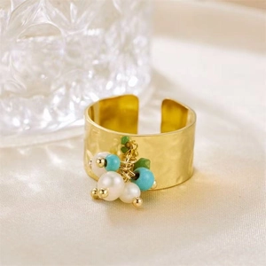 Detail of wide gold ring with white pearls, turquoise beads and green stones on silk background