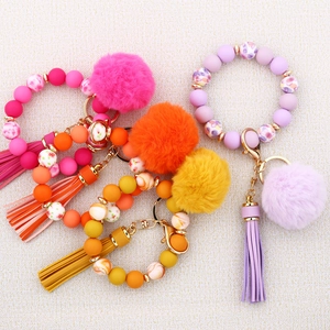 Detail of colorful silicone bead bracelets with leather tassels and plush pom-poms