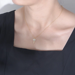 Macro shot of 925 silver key pendant necklace with cubic zirconia on model's neck