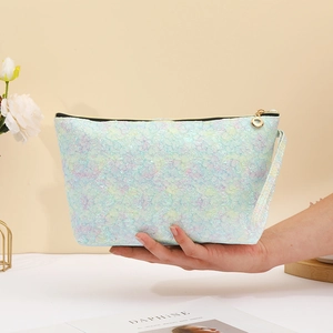 Detailed view of iridescent lace cosmetic bag with gold zipper and a handy wristlet