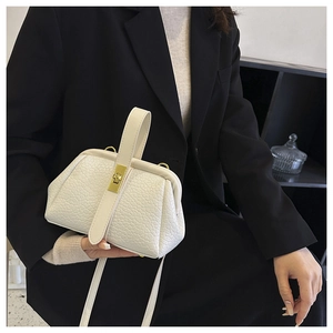 Detailed shot of white embossed leather handbag with gold buckles and adjustable strap