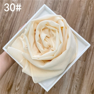 Vue détaillée du foulard en mousseline crème avec paillettes dorées plié en forme de rose