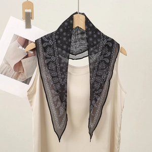 Detailed macro shot of a black paisley bandana hanging on a wooden hanger with a beige top
