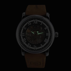 Luminous hands and Roman numerals on a skeleton mechanical watch face in the dark