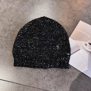 Sparkling black sequin knitted beanie hat with a metal B logo on a gray background