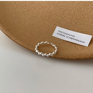 Close-up of minimalist silver beaded open ring with adjustable band and metallic luster