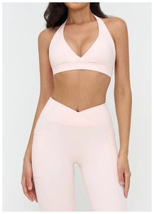 Dettaglio dei pantaloni da yoga a vita alta con cintura a V e tasche laterali rosa