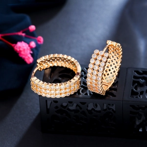 Macro shot of gold hoop earrings with sparkling zircon inlay and hollow grid detail