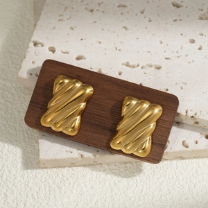 Minimalist gold square earrings with wavy texture and polished finish on stone background