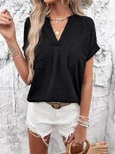 Detail of black V-neck short sleeve blouse featuring textured dot fabric and front pockets