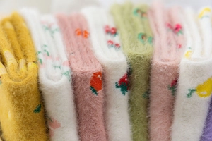 Detail of folded plush mink velvet socks in various colors with floral embroidery