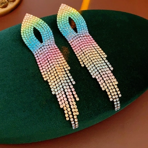 Macro shot of colorful gradient rhinestone tassel earrings on a green velvet mat