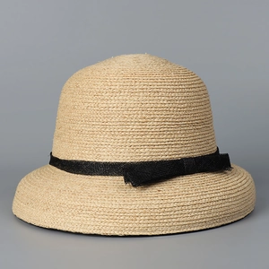 Close-up of raffia sun hat texture featuring a black mesh ribbon and delicate bow detail
