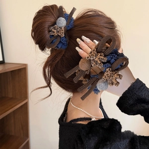 Detailed view of leopard print bow and knit hair scrunchies on a low bun hairstyle