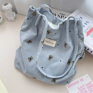Detailed view of light blue corduroy tote bag featuring cute cartoon bear print and metal clasp