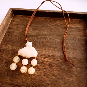 Close-up of resin cloud pendant with beaded fringe on a rustic wooden tray