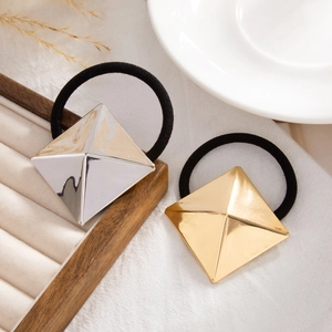 Close-up of gold and silver pyramid geometric hair ties on a wooden jewelry tray