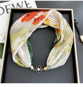 Detail of floral pleated scarf with magnetic black and gold flower brooch and pearl