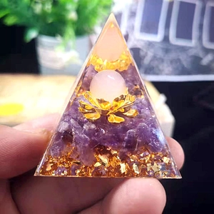 Close-up of crystal pyramid with amethyst chips, rose quartz ball, and golden lotus base