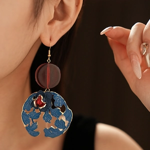 Close-up of vintage flower earrings with blue petals and red floral center