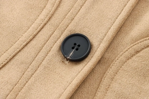Gros plan sur un bouton noir mat et le tissu en daim chamoisé de la veste courte