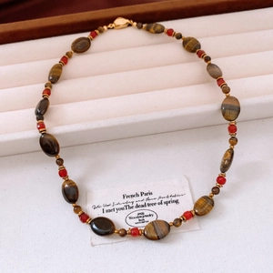 Détail du collier de perles en œil de tigre plaqué or 18 carats dans un coffret à bijoux blanc