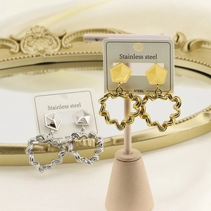 Detailed view of gold and silver stainless steel heart earrings with textured surface