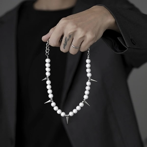 Hip hop pearl necklace with silver metal spikes shown against a black suit background