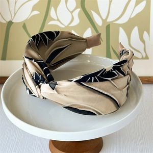 Close-up of wide knotted headband with beige and black abstract floral print pattern