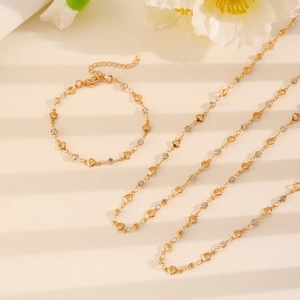 Flat lay of gold Y-necklace and bracelet set with heart charms and sparkling crystals