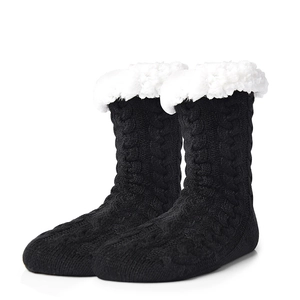 Close-up of black cable-knit slipper socks with warm white faux fur trim and cozy lining