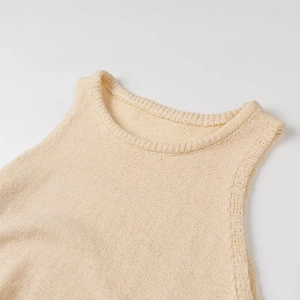 Dettaglio del top beige senza maniche in maglia con trama a coste sullo scollo rotondo