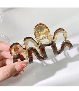 Macro detail of amber leopard print hair claw with wavy design and gold metal spring