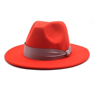 Close-up of red wool fedora hat featuring a wide grey satin ribbon and rhinestone buckle