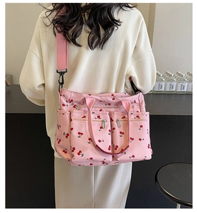 Detail of pink cherry print nylon tote bag with multiple pockets and wide shoulder strap