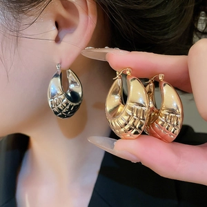 Detail showing metallic round earrings with quilted textured pattern in gold and silver finish