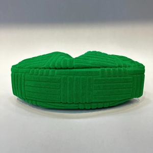 Detail shot of green evening handbag featuring a unique woven texture and wooden handle