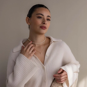Close-up of a model wearing a layered gold birthstone necklace and pearl choker set