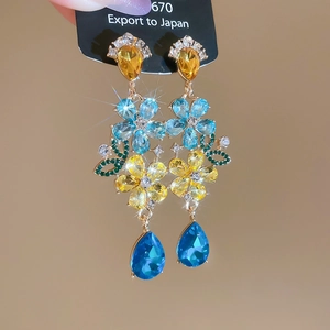 Macro shot of colorful crystal drop tassel earrings featuring blue and yellow stones